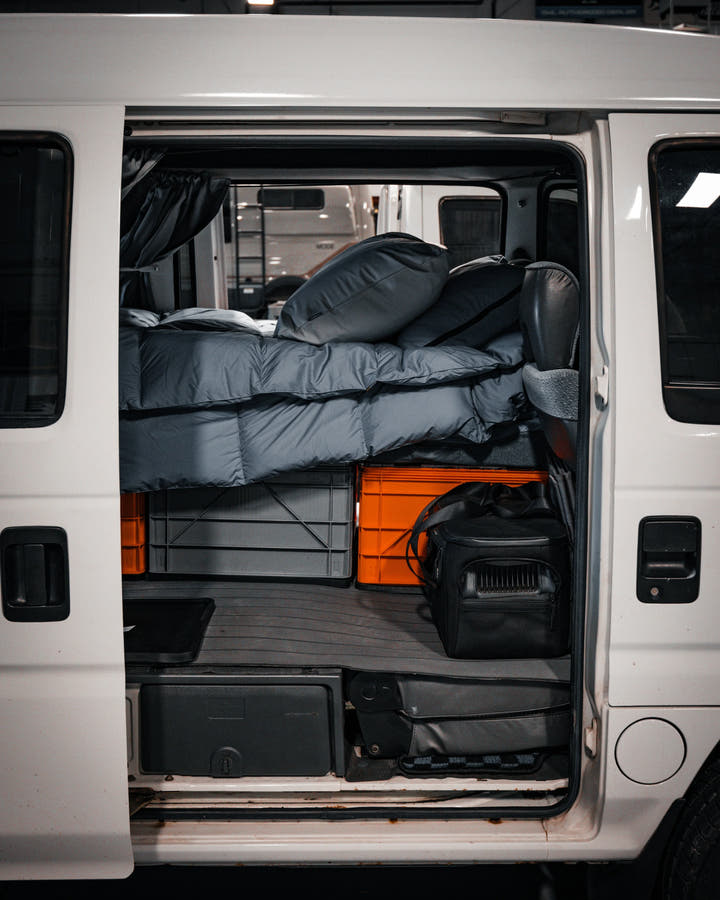 Grey and orange SidioCrate storage bins installed in the back of a camper van.