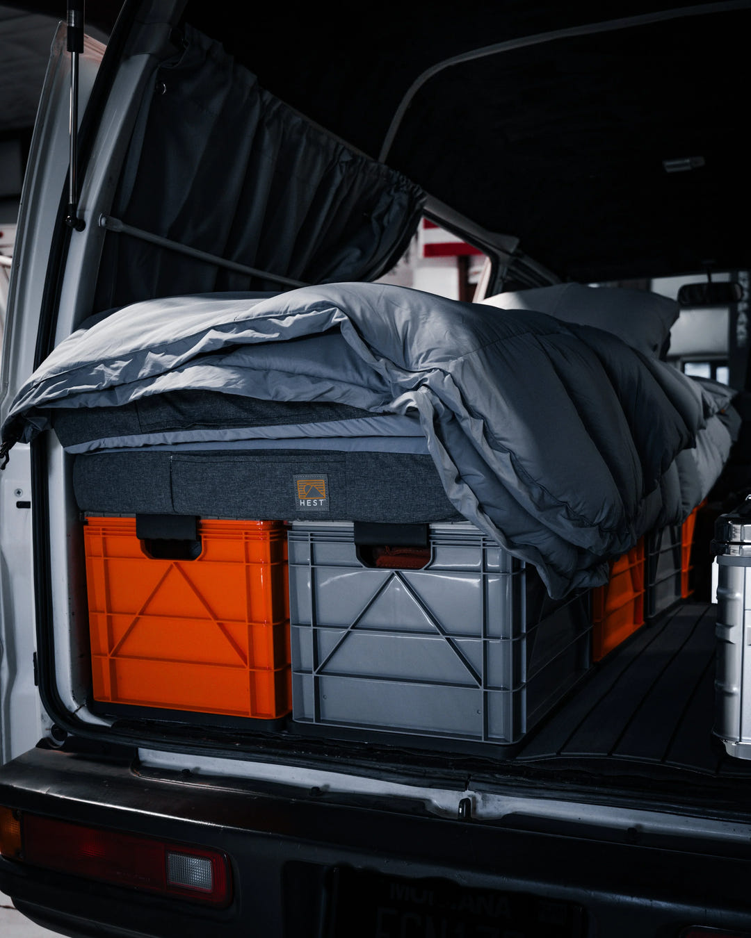 SidioCrate orange and grey storage crates under a grey mattress in a camper van.