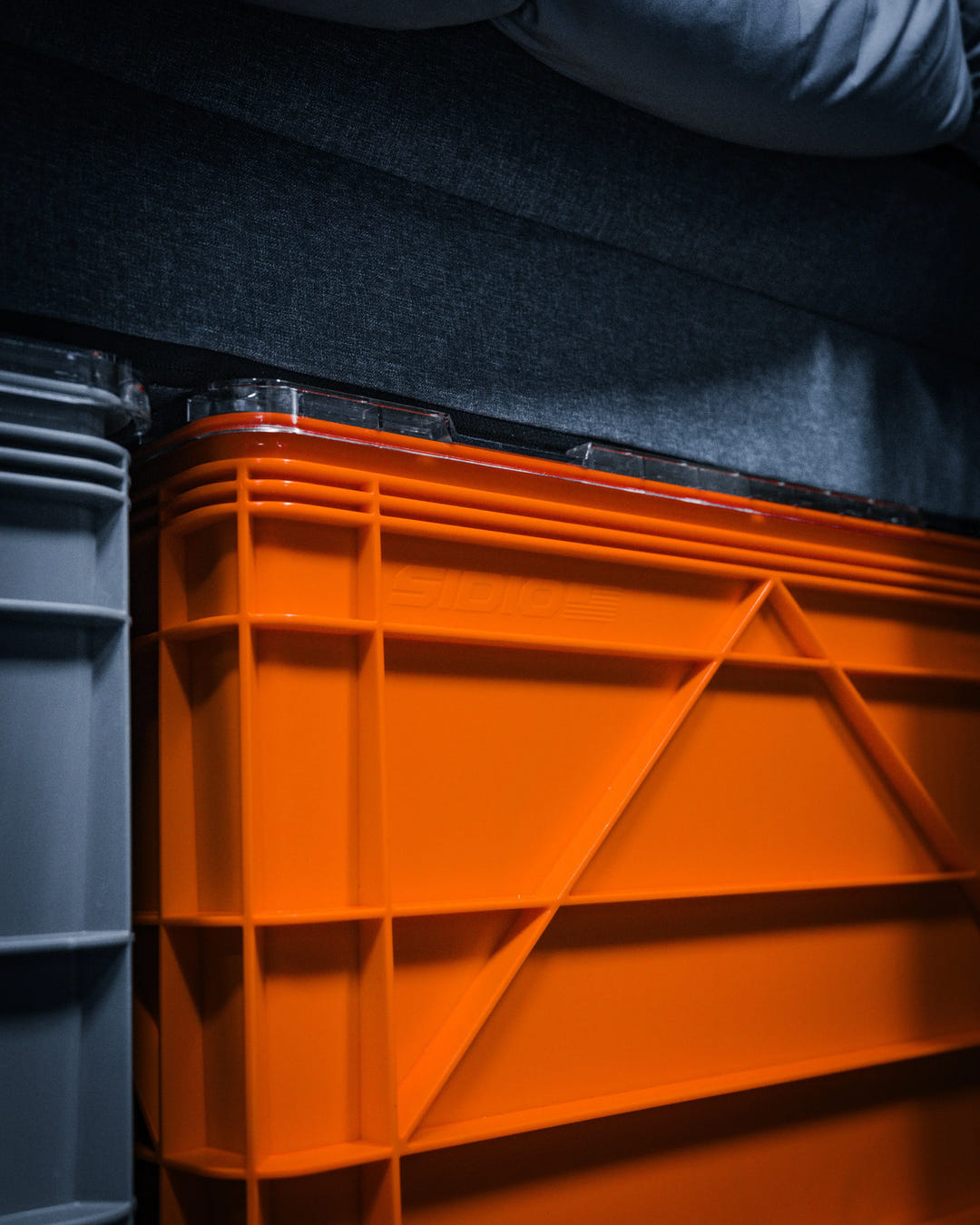 Orange plastic SidioCrate storage bin mounted in a camper van.